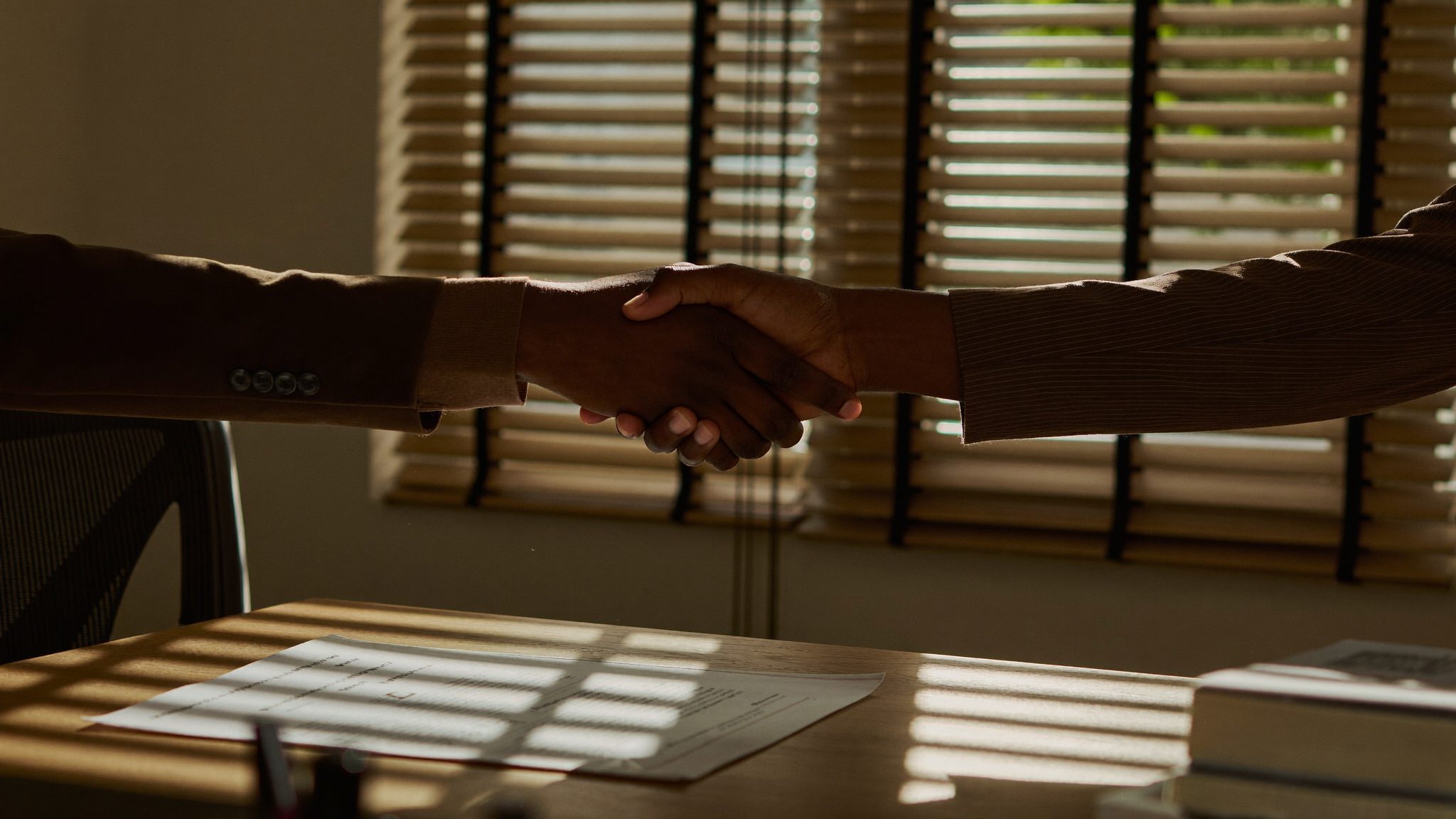 Adviser and client shaking hands over a desk at a Polokwane office